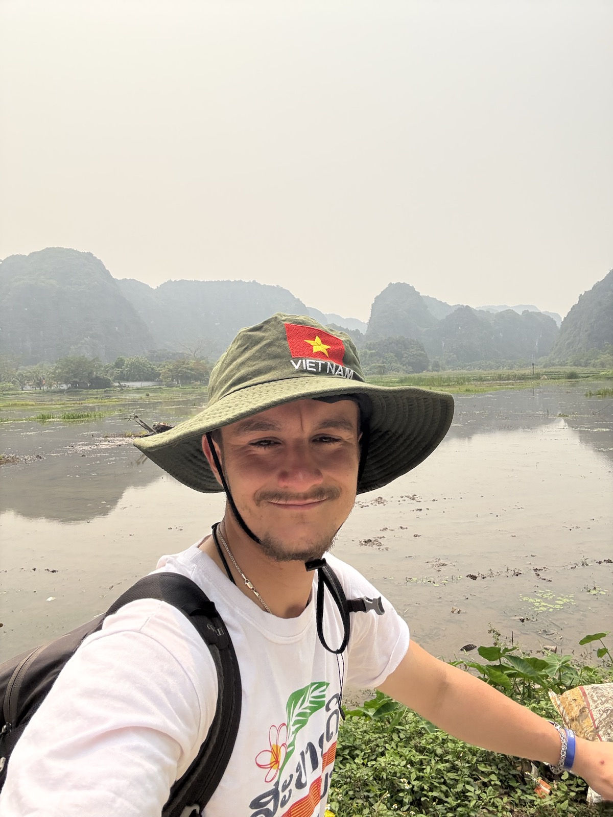 Ollie smiling beside a river and limestone mountains in Vietnam